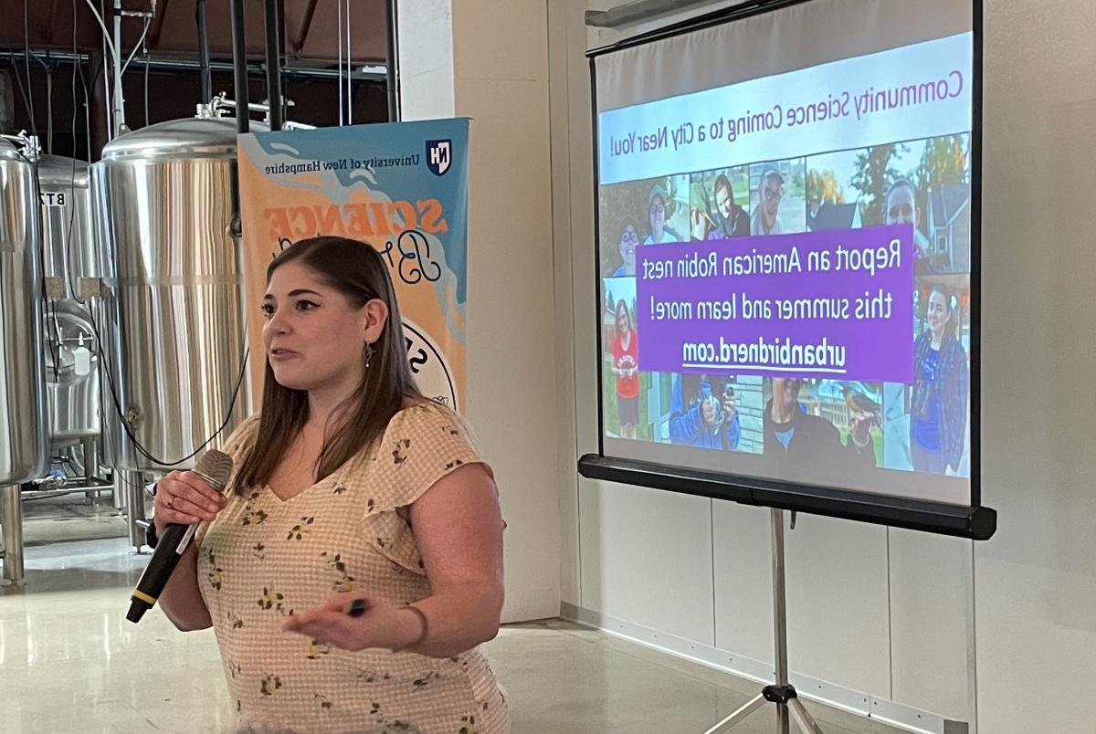 Woman stands in front of a screen giving a presentation at a brewery