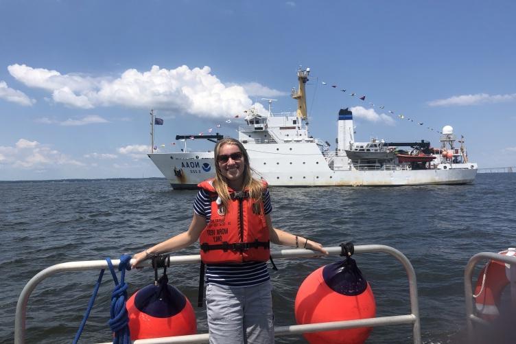 Natalie 烹饪 stands on a ship in front of the Thomas Jefferson hydrographic vessel.