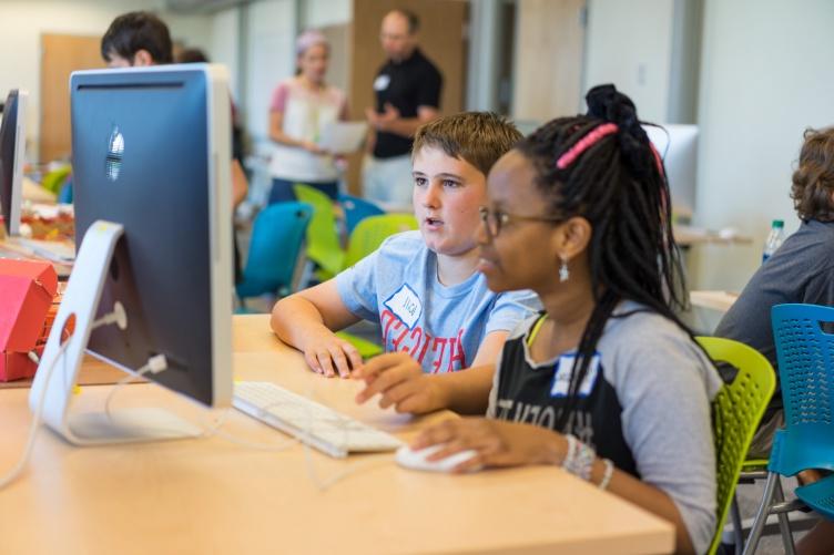 Two middle school students, a boy and a girl, work together on a computer.