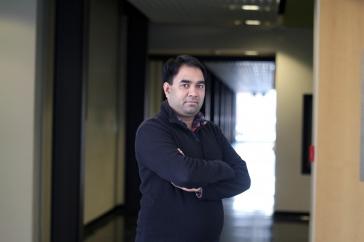 Researcher Harish Vashisth stands with arms crossed in darkened hallway