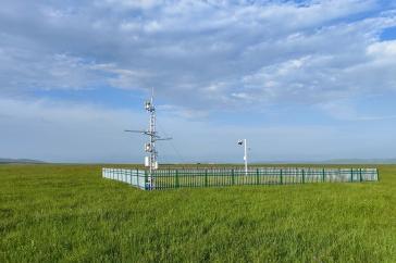 Scientific instruments sit in a green field below a blue sky.