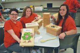 three women in classroom showing their woodworking projects