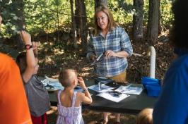 Woman in plaid shirt holds whale baleen so library patrons can see