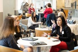 alumnae and students at round tables, talking, in Ham Smith Great Hall