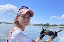 Female graduate student on a boat holding a male blue crab