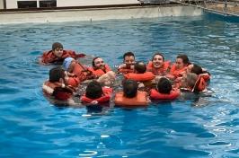 Group of people wearing lifejackets huddle in a circle in a pool