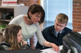 Female professor leans over two college students