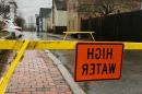 Flooded road blocked with yellow tape and "high water" sign