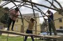 Three people building a wigwam.